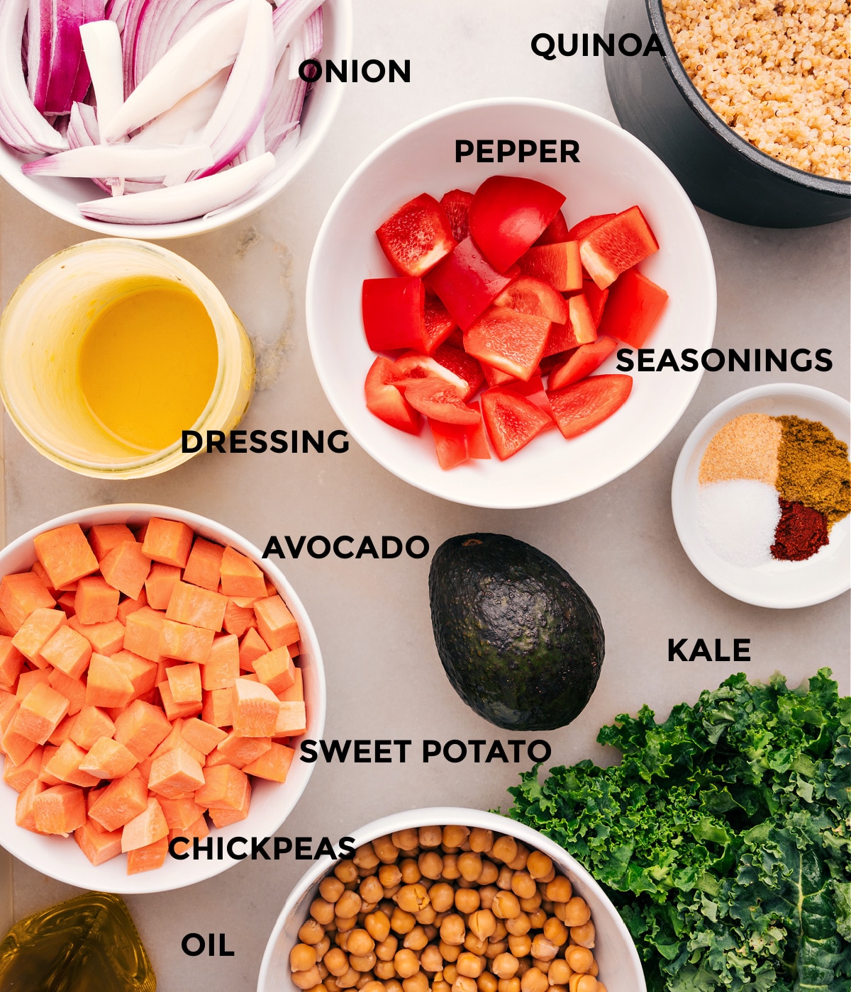 All the ingredients in this recipe are prepped, including veggies, seasonings, quinoa, chickpeas, oil, and dressing.