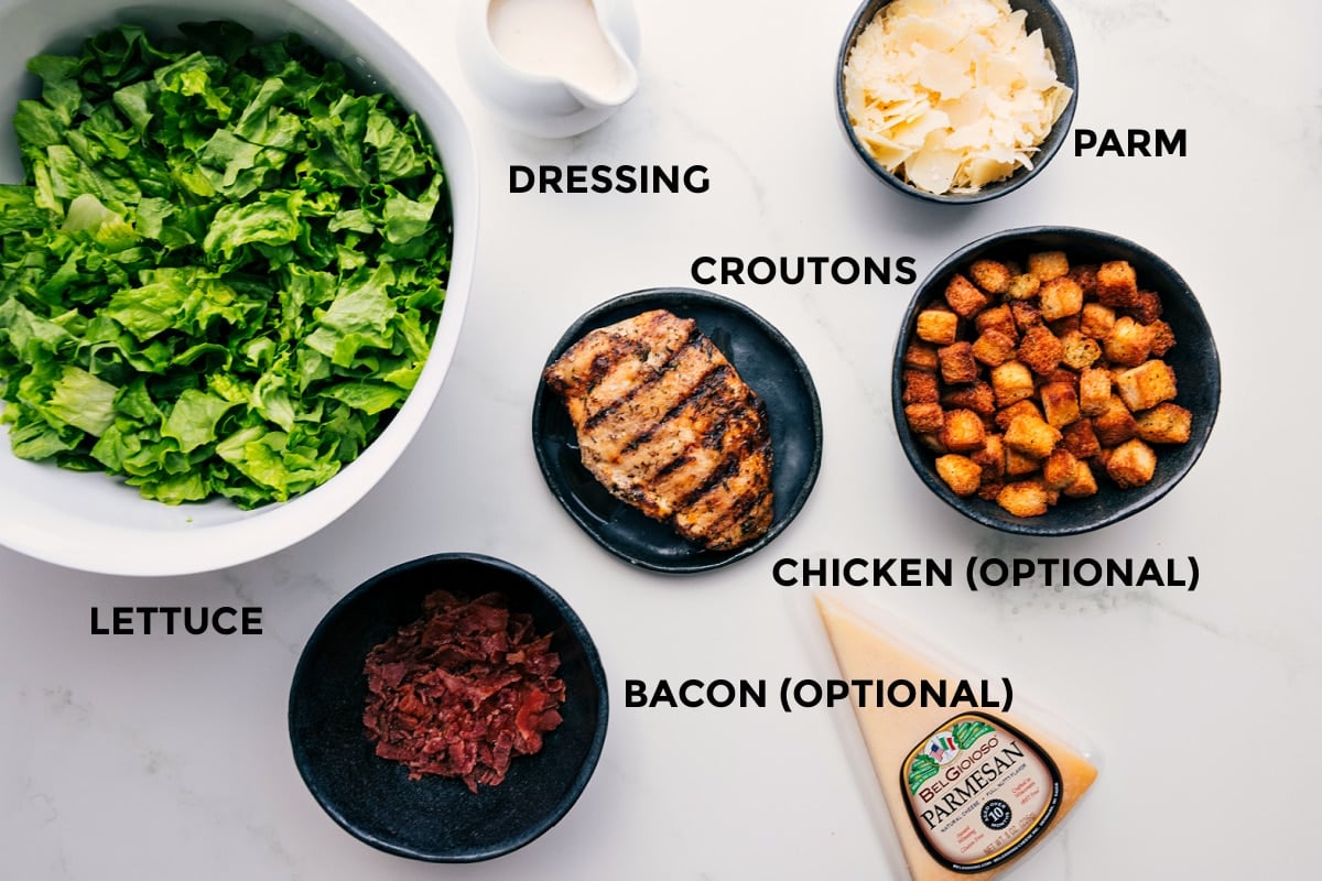 All the ingredients prepped and ready for easy assembly: lettuce, dressing, Parmesan, croutons, bacon, and chicken.