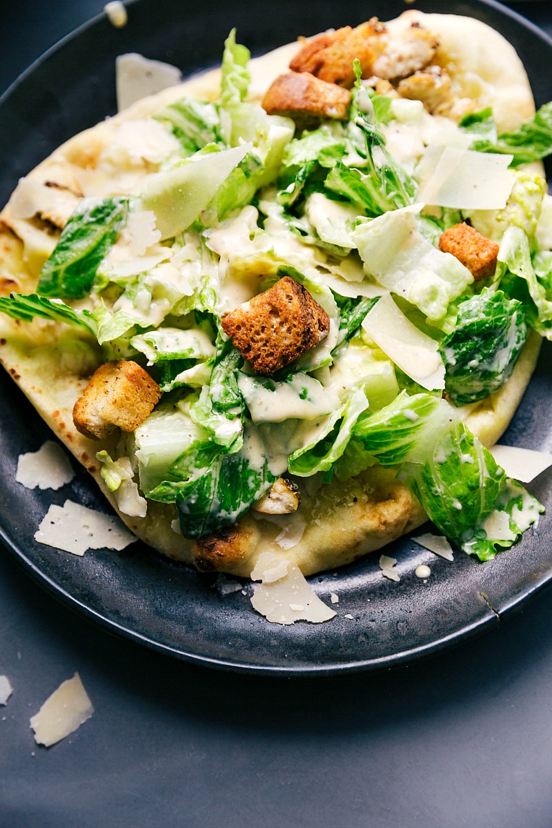 Overhead up close image of the Caesar =Salad Pizza on a plate ready to be eaten.