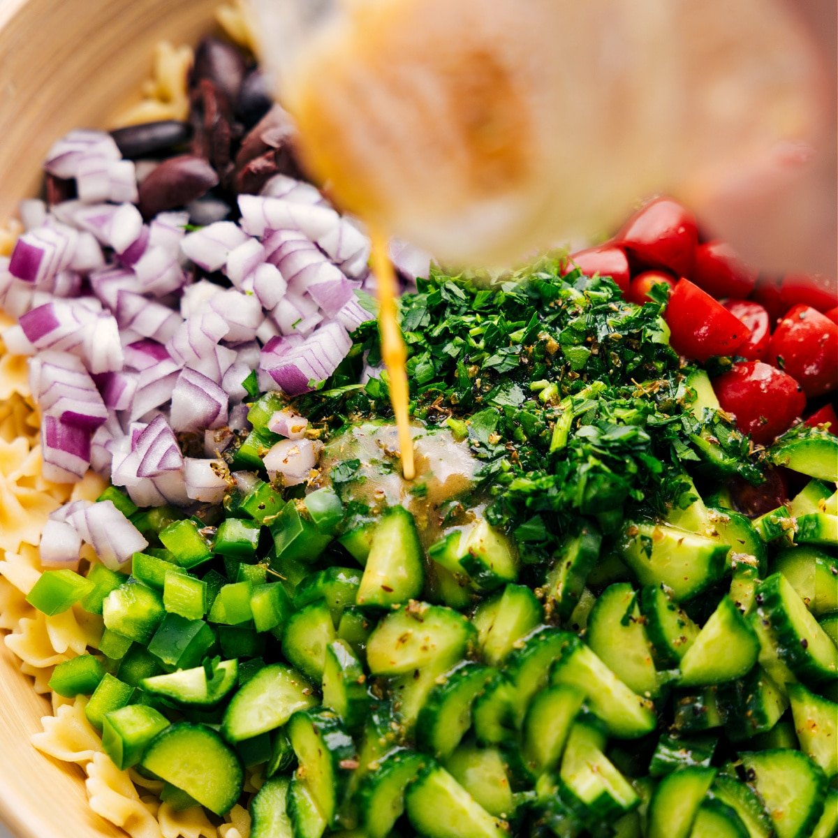 The dressing being poured over the Greek Pasta Salad.