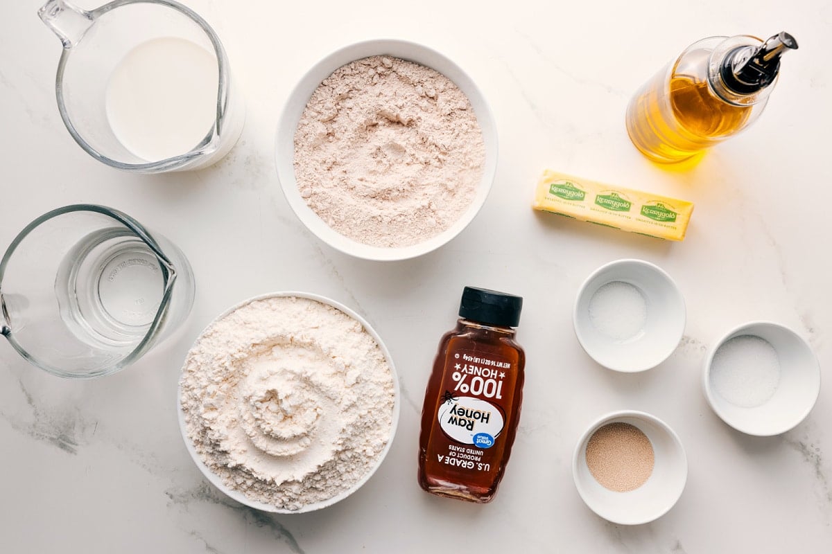 Ingredients in this recipe prepped out for easy assembly including milk, water, flour, honey, yeast, salt, sugar, butter, and oil.