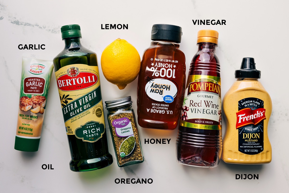 All the dressing ingredients prepped for easy assembly, including garlic, olive oil, lemon, oregano, honey, vinegar, and Dijon.