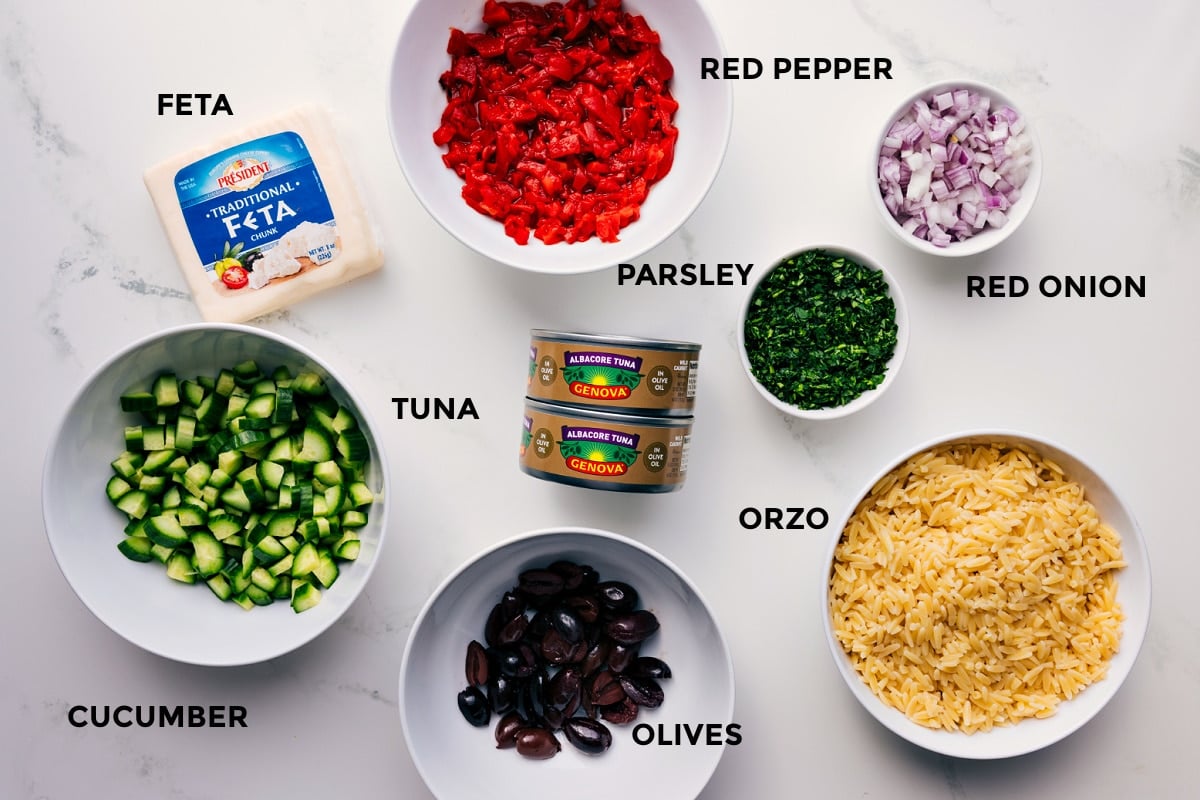 All the ingredients for Mediterranean Tuna Salad prepped for easy assembly, including feta, red pepper, red onion, parsley, orzo, olives, tuna, and cucumber.