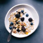 Homemade muesli cereal in a bowl with milk and berries, ready for a healthy and delicious breakfast.