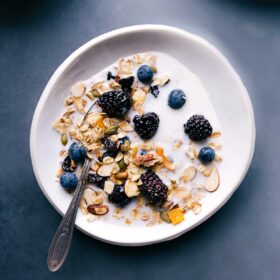 Homemade muesli cereal in a bowl with milk and berries, ready for a healthy and delicious breakfast.