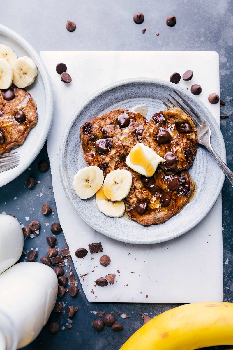 Gluten free banana pancakes with melted chocolate chips inside, topped with fresh banana slices, prepared for a delicious breakfast.