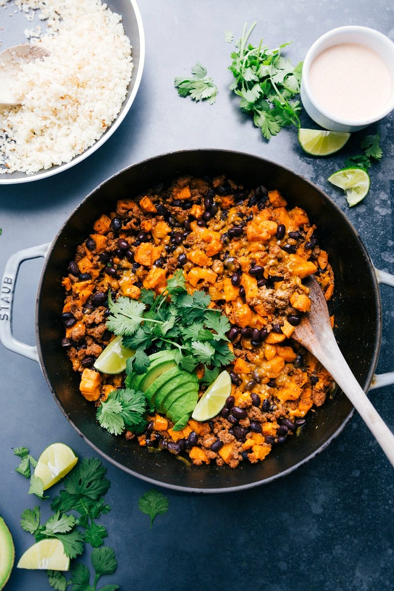 A pan full of ground turkey sweet potato skillet, accompanied by a bowl of rice, presenting a hearty and savory meal.