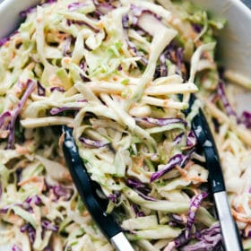 Coleslaw being scooped up with tongs for BBQ Chicken Sandwiches, adding a perfectly complimentary flavor.