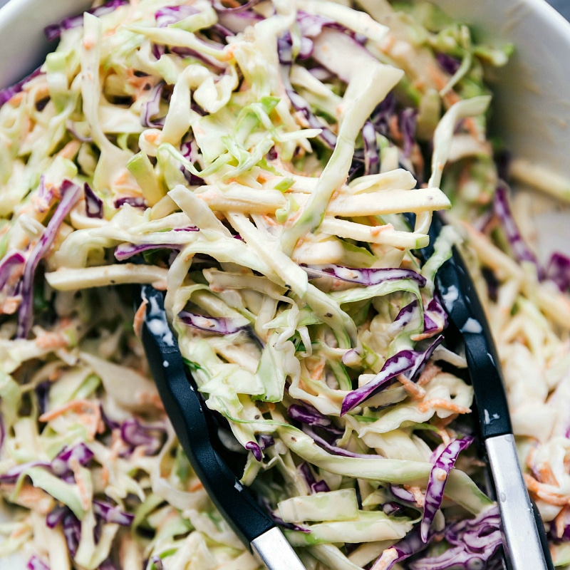 Overhead image of the coleslaw being scooped up by the tongs for BBQ Chicken Sandwiches.