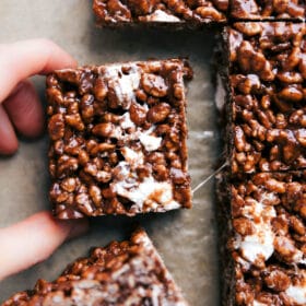 Chocolate rice krispie treats cut and being pulled apart to reveal its crunchy and gooey texture, a delicious twist on a favorite dessert.
