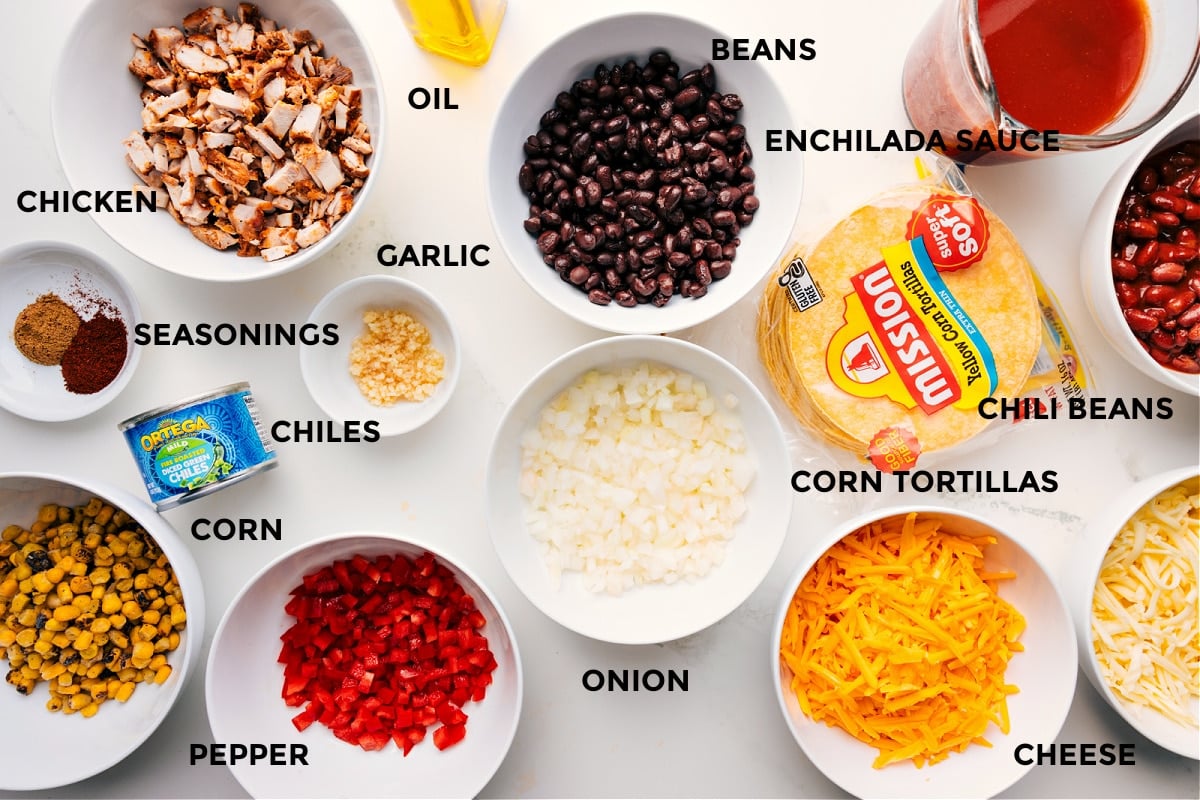 Ingredients In Chicken Enchilada Sauce All the ingredients for Chicken Enchilada Casserole prepped and ready to assemble, including chicken, seasonings, corn, peppers, green chiles, garlic, oil, beans, enchilada sauce, chili beans, corn tortillas, onion, and cheese.