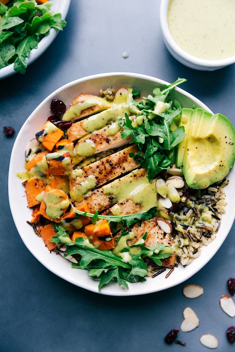 Chicken and wild rice in a bowl, featuring well-cooked, sliced chicken and creamy sauce poured on top, creating a healthy and delicious meal.