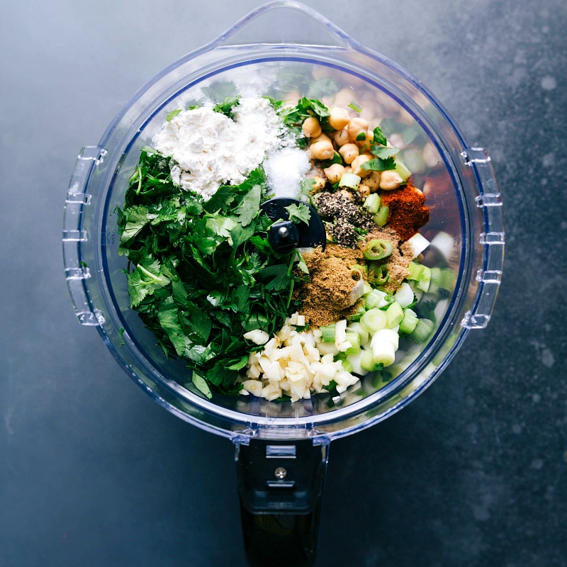 Making falafel by adding all ingredients into a food processor as part of the falafel recipe preparation.