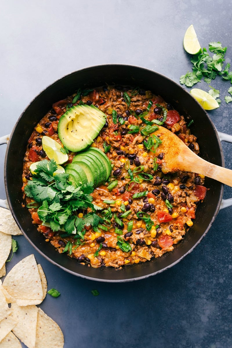 A finished turkey taco skillet, garnished with avocado slices, cilantro, and lime, creating a warm and hearty meal.