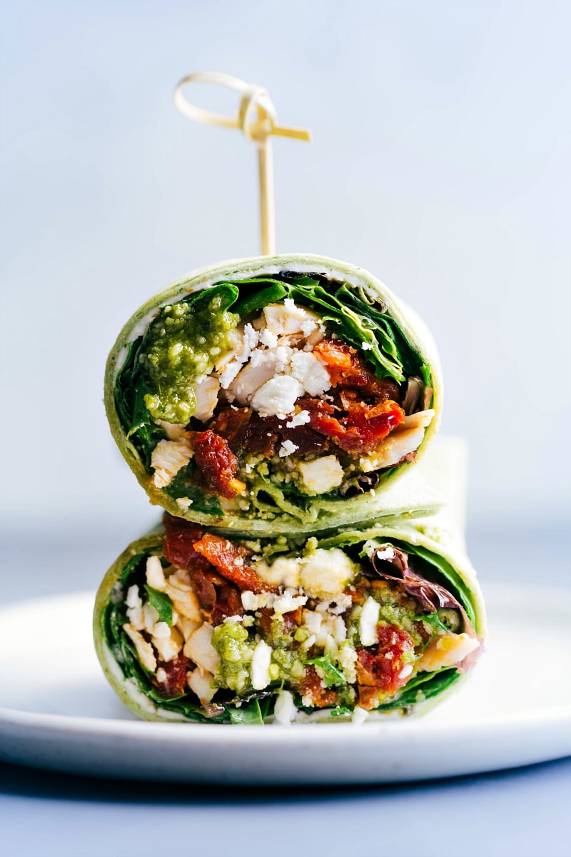 Stacked halves of mediterranean wraps on a plate, showcasing the delectable ingredients inside.