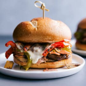 Ham and cheese hoagie with roasted veggies and cheese spilling out, presenting a delicious and savory sandwich.