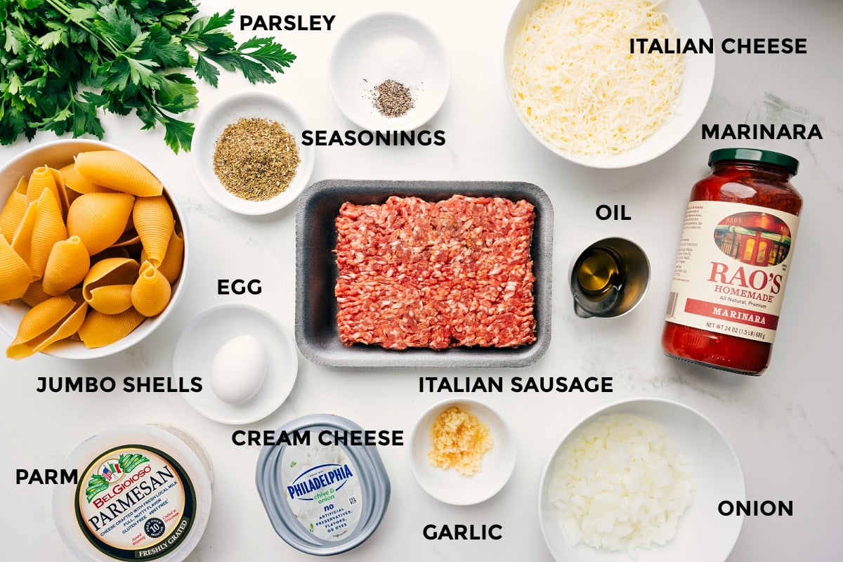Ingredients In Stuffed Shells With Sausage Ingredients for stuffed shells prepped for easy assembly, including jumbo shells, Parmesan, cream cheese, egg, seasonings, Italian sausage, garlic, onion, marinara, oil, and Italian cheese.