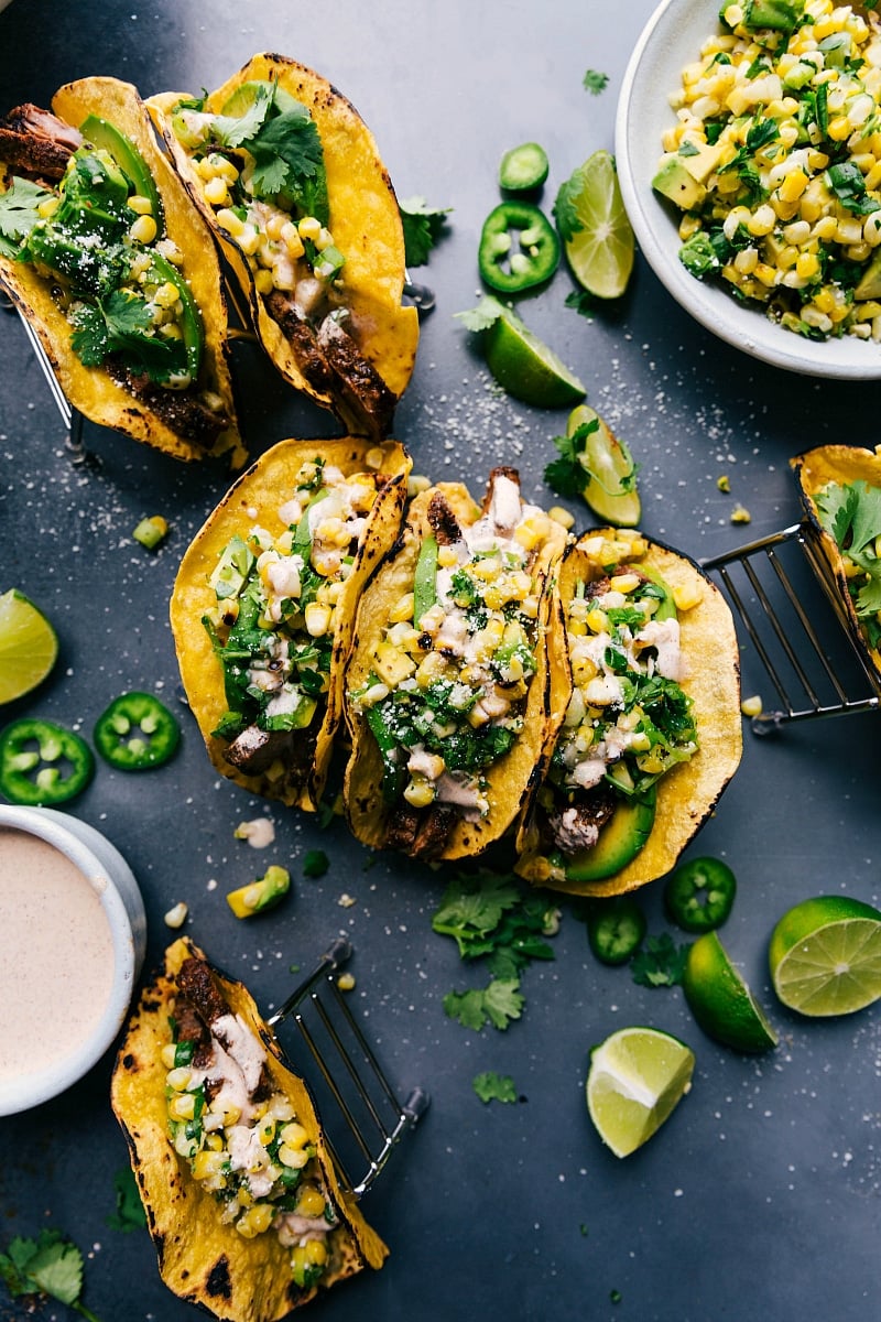 Delicious steak tacos garnished with corn salsa, cheese, and various toppings, prepared and served.