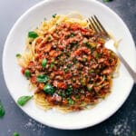 Savory and delicious turkey bolognese on a bed of spaghetti, topped with fresh herbs.