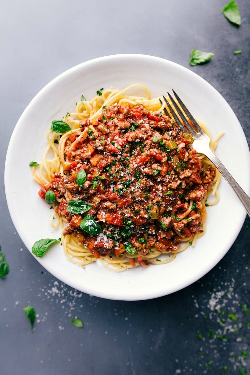 Savory and delicious turkey bolognese on a bed of spaghetti, topped with fresh herbs.