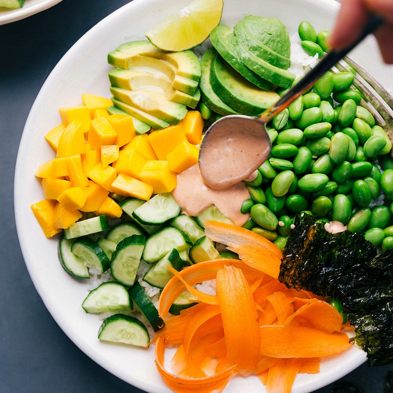 Overhead view of the spicy sauce being drizzled on Vegetarian Sushi Bowls.