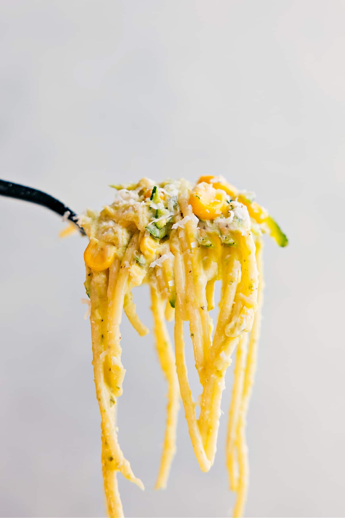 A forkful of the pasta being held up showing all the yummy components to it.