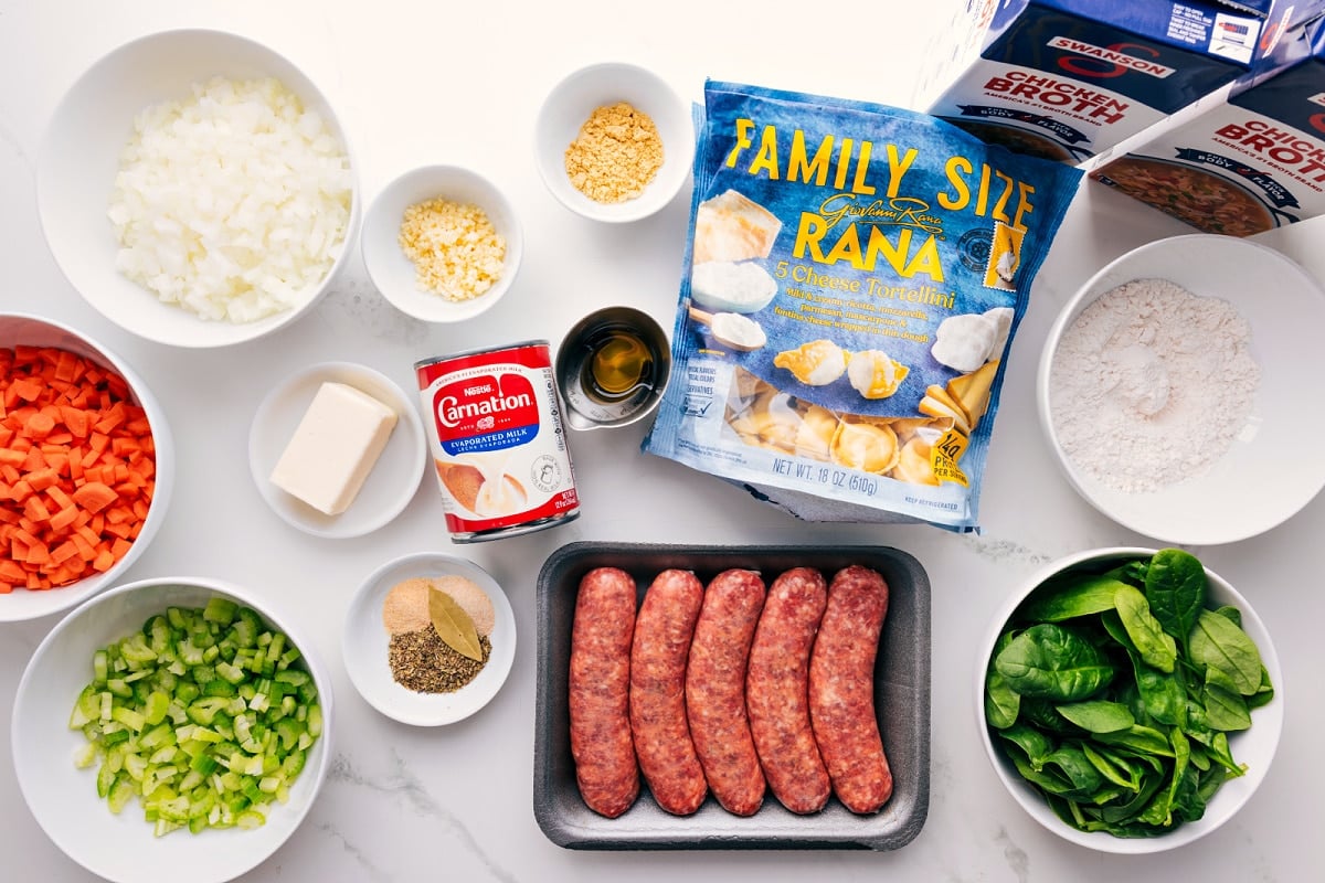 All the ingredients in this recipe prepped out for easy assembly including the veggies, butter, seasonings, evaporated milk, garlic, tortellini, sausage, flour, and chicken broth.