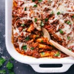 Finished baked ziti in a casserole dish, with a scoop taken out to reveal the warm, flavor-packed layers inside.