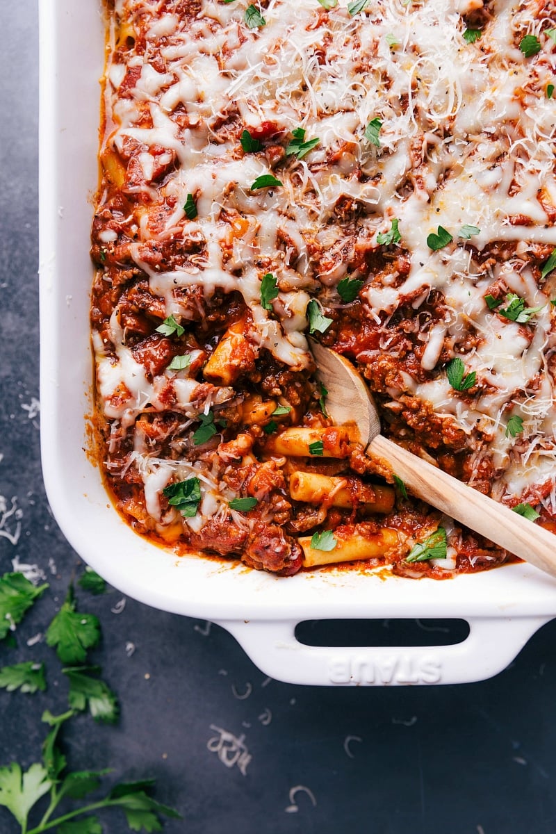 Finished baked ziti in a casserole dish, with a scoop taken out to reveal the warm, flavor-packed layers inside.