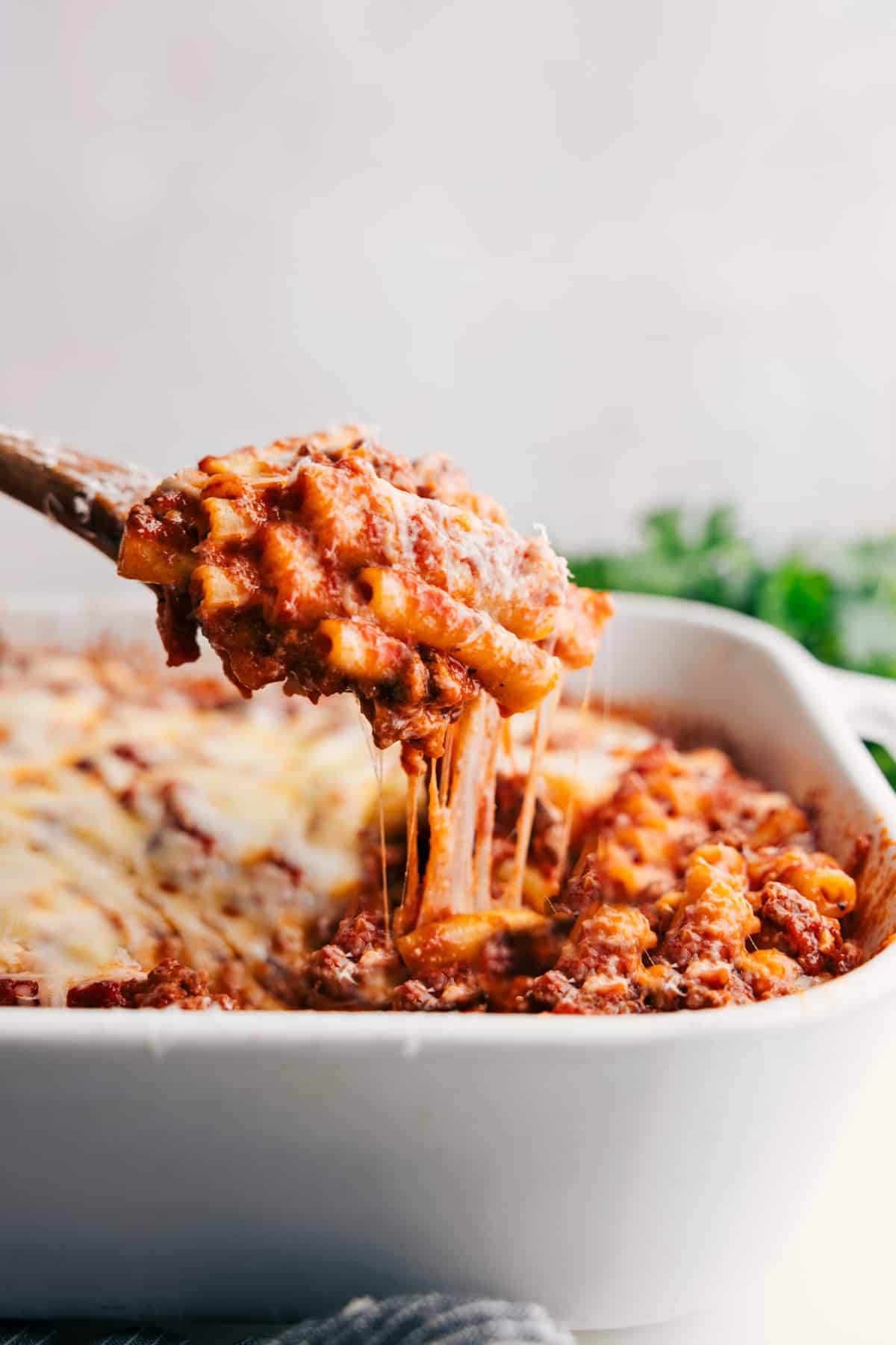 Warm and Delicious Baked Ziti Ready to Serve Baked Ziti Recipe in a baking dish with a large spoonful scooped out, showing the cheesy layers and rich meat sauce.