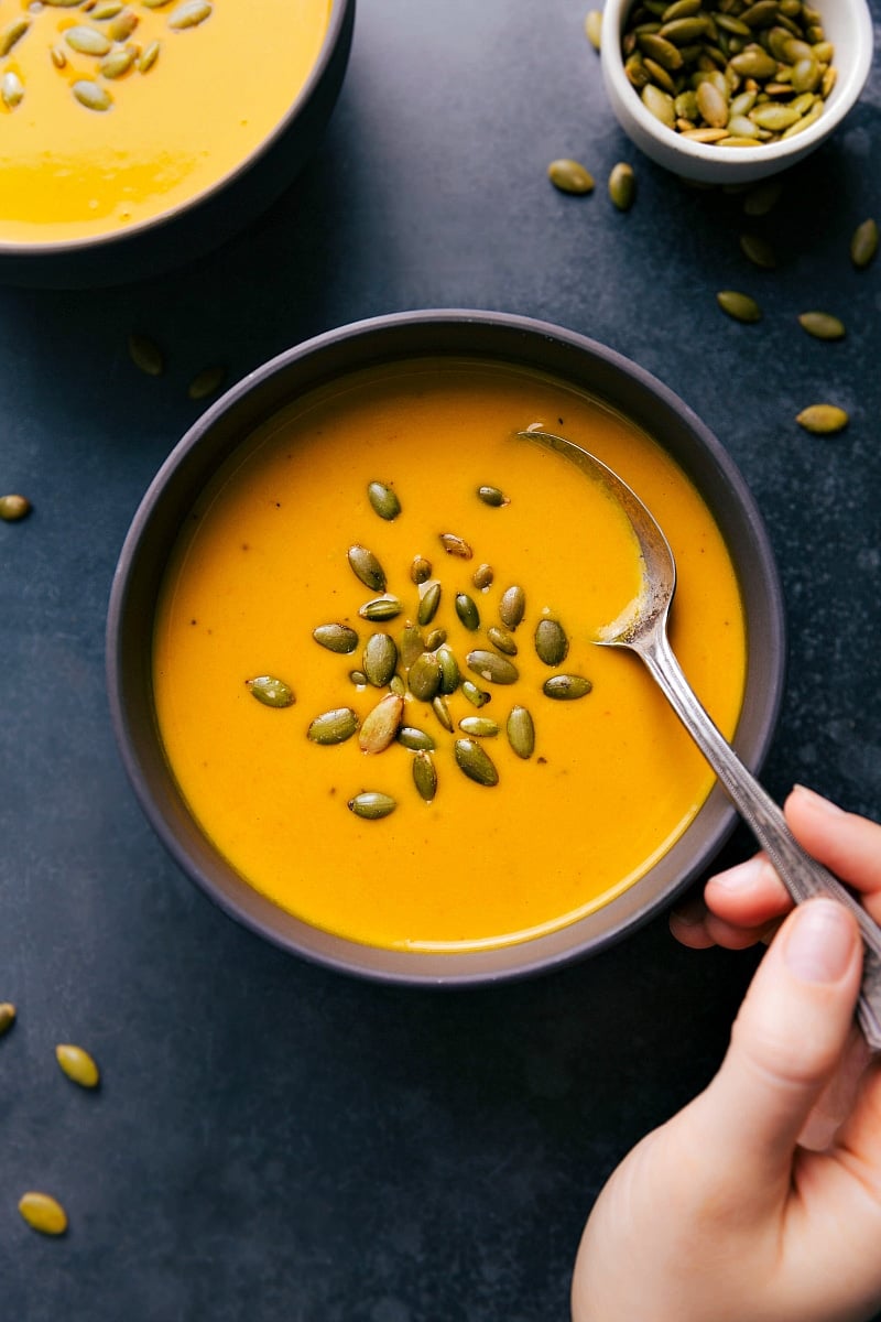 Overhead image of Carrot Soup in a bowl with pepita seeds on top.