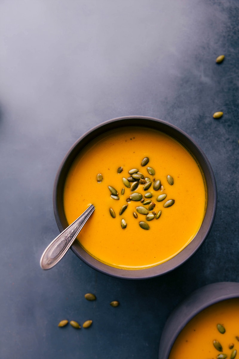 Overhead image of a bowl of Carrot Soup with a spoon it, ready to be eaten