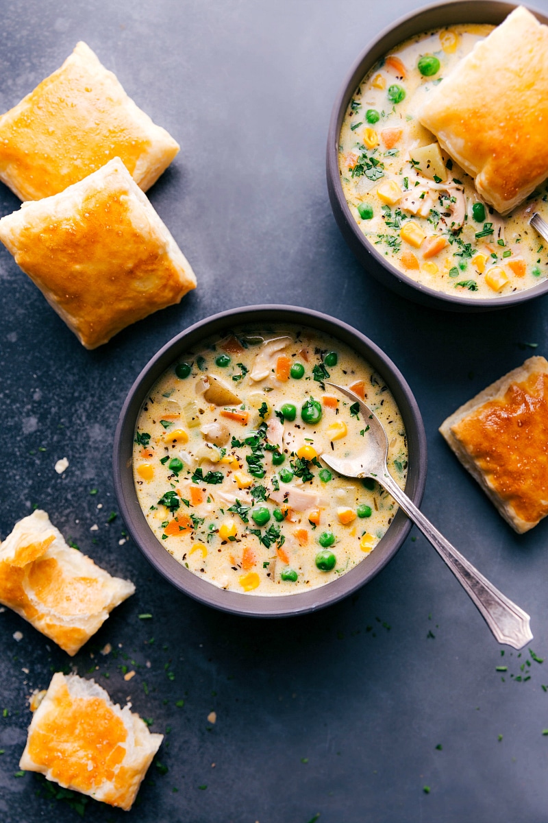 Overhead image of two bowls of Chicken Pot Pie Soup with the fresh puff pastry scattered around the bowl.