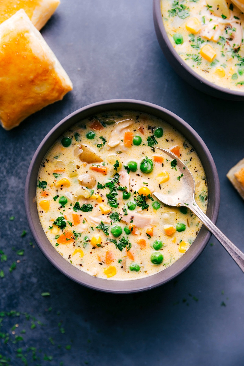 Chicken pot pie soup in a bowl with hearty ingredients including chicken and vegetables, topped with fresh herbs.