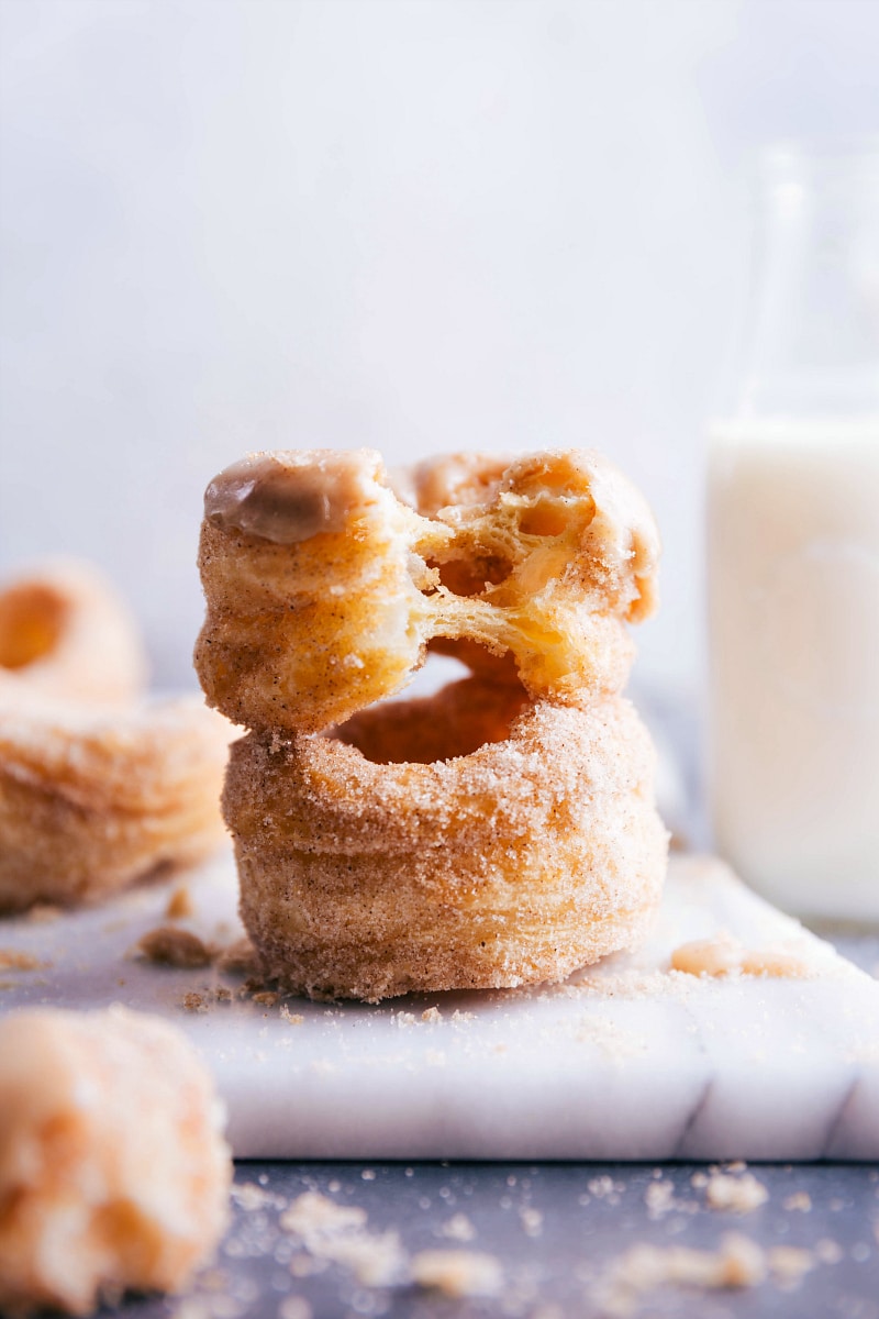 Two cronuts, one bitten to reveal the fluffy, layered interior.