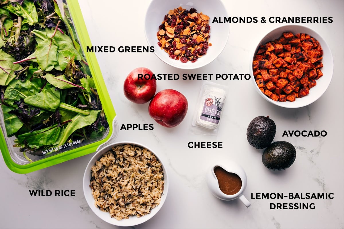 All the ingredients prepped out for easy assembly including mixed greens, wild rice, almonds, cranberries, roasted sweet potatoes, avocado, cheese, and dressing.