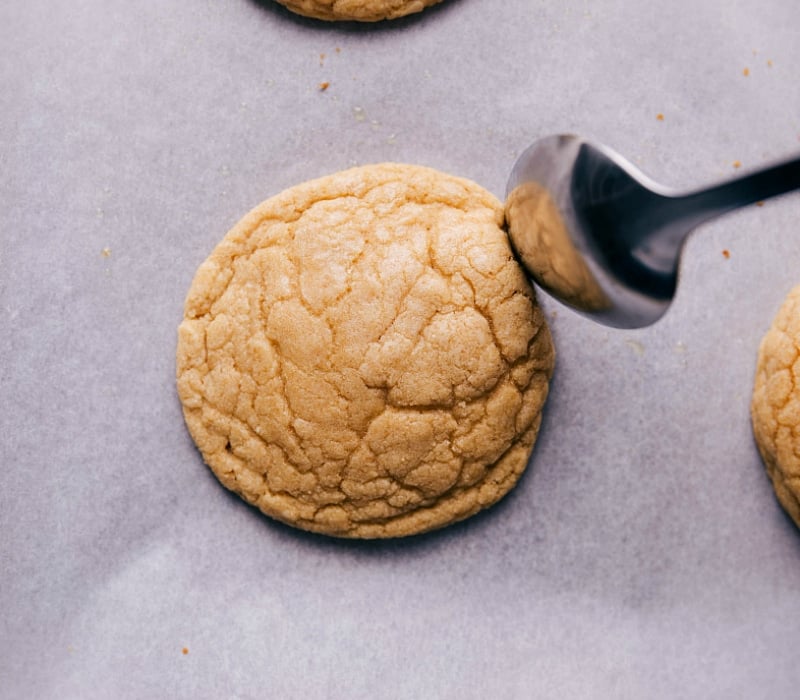 Using the back of a spoon to push in the edges of just-baked cookies, creating crispy edges while the cookies are still warm.