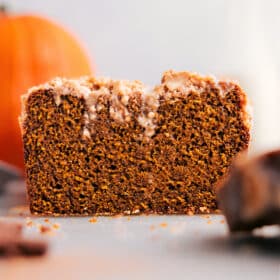 Pumpkin bread with streusel topping, slice removed, showcasing its deliciousness.