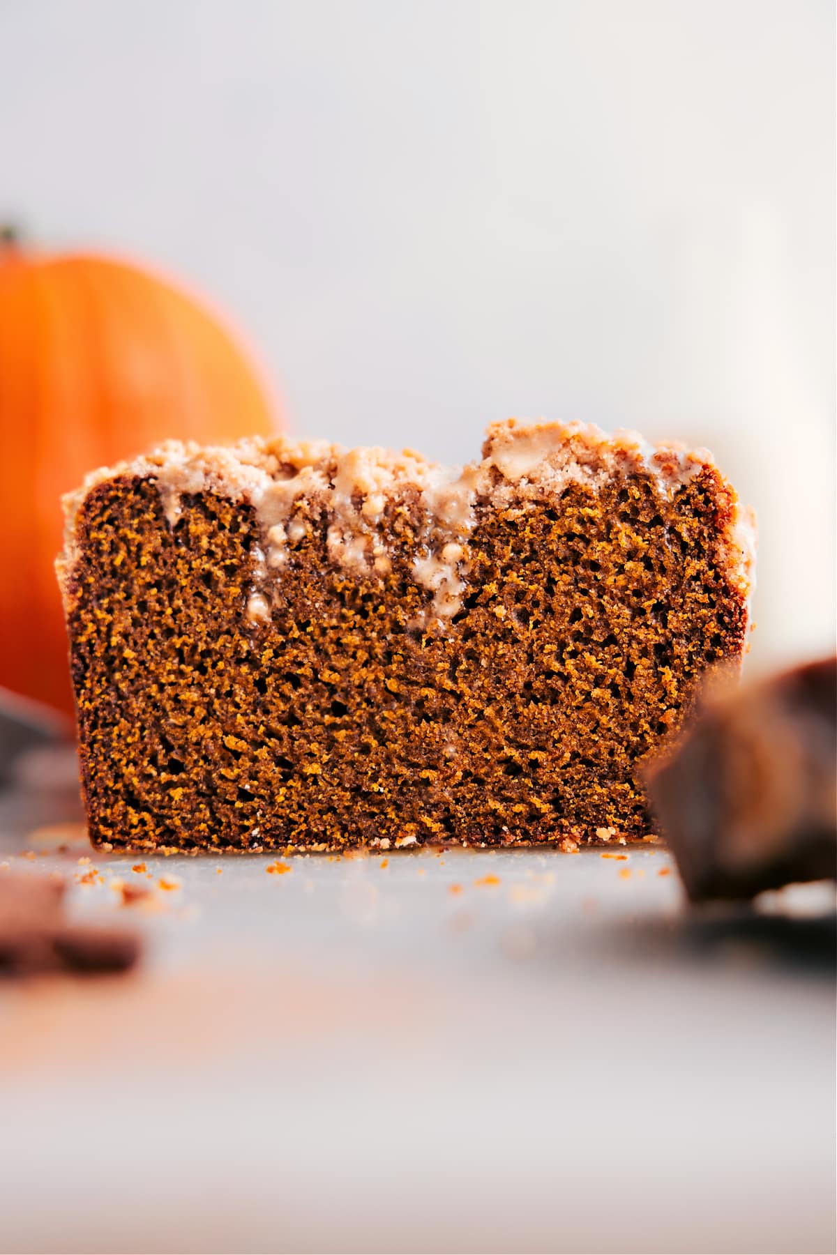 Pumpkin bread with streusel topping, slice removed, showcasing its deliciousness.