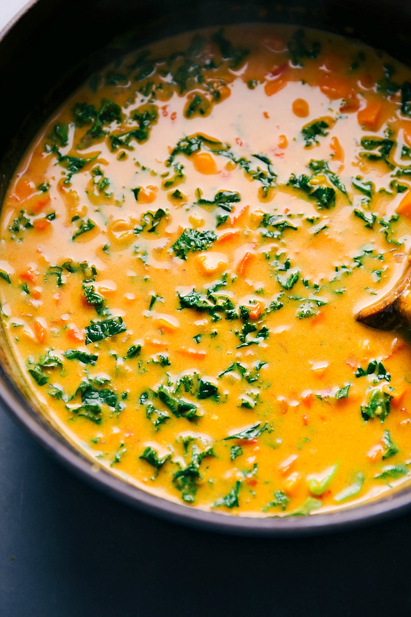 A pot full of rich and creamy coconut curry sweet potato soup with tender chunks of sweet potato and vibrant kale.