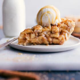 Slice of apple pie with ice cream and caramel sauce on top.