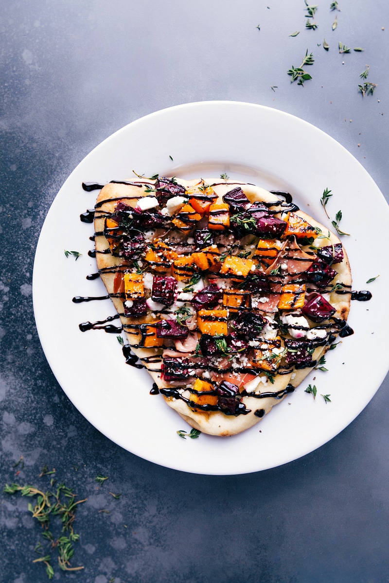 Overhead image of the beet and goat cheese flatbread with a balsamic glaze over it all ready to be served