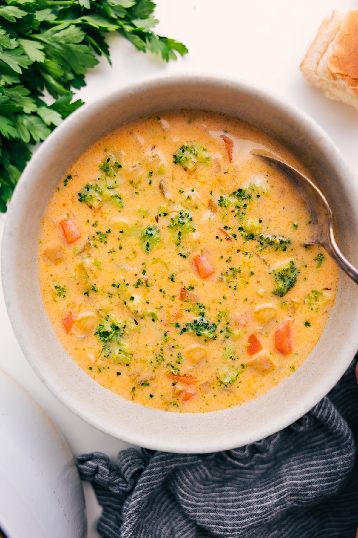 This creamy, hearty Broccoli Potato Soup is loaded with crisp-tender broccoli, golden buttery potatoes, and even more veggies. On a cold, drizzly day, there's nothing like enjoying this soup served in a crusty sourdough bread bowl or with dinner rolls for dipping! Recipe via ChelseasMessyApron.com #broccolisoup #potato #broccoli #soup #warming #wintery Broccoli Potato Cheese Soup served in a bowl with a spoon.
