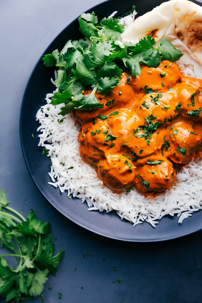 Overhead view of a plate of Butter Chicken Meatballs on a bed of rice.