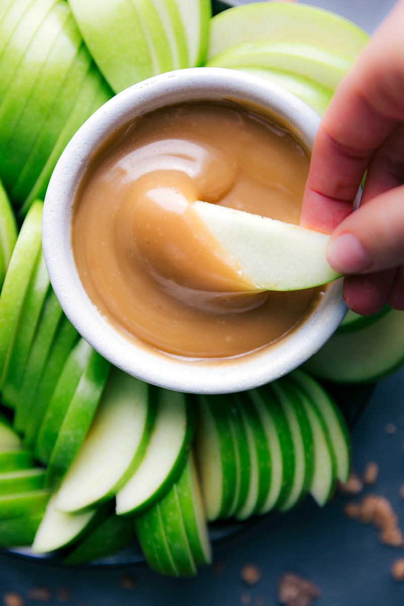 Close-up view of Caramel Sauce with an apple slice being dipped in.