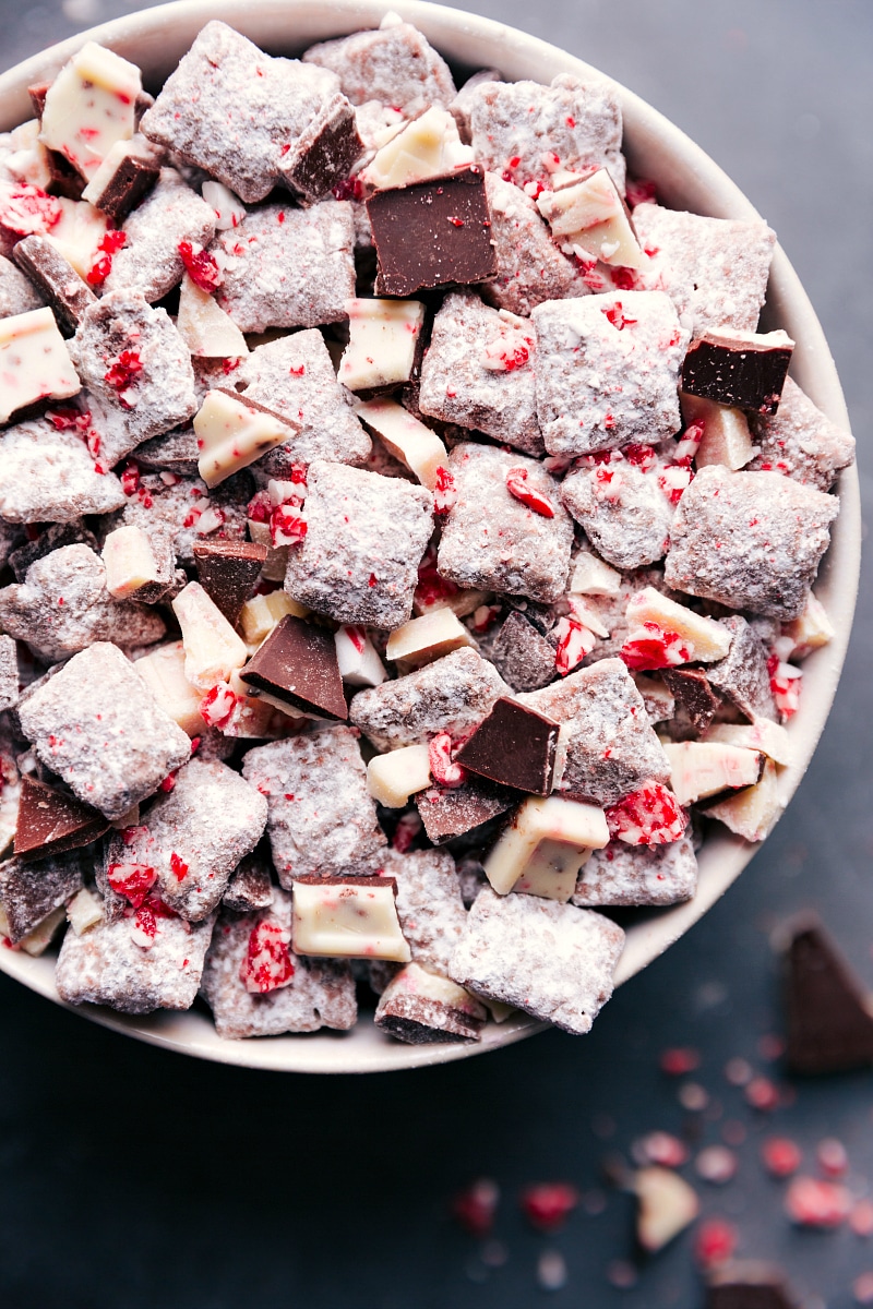 Chex mix muddy buddies peppermint bark in a bowl, a delicious and festive snack, coated in powdered sugar and crushed peppermint, ready to be enjoyed by everyone.