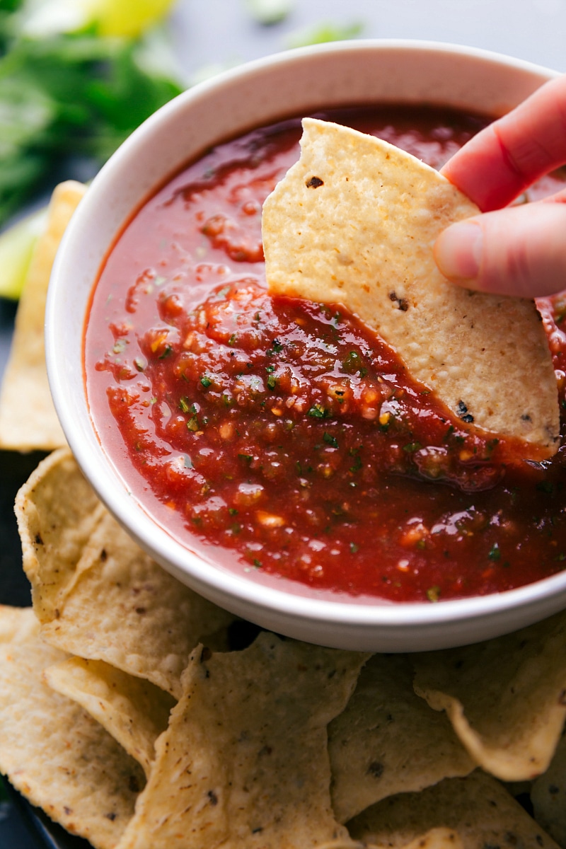 A chip being dipped into the salsa, scooping up a perfect bite of delicious and flavorful salsa.
