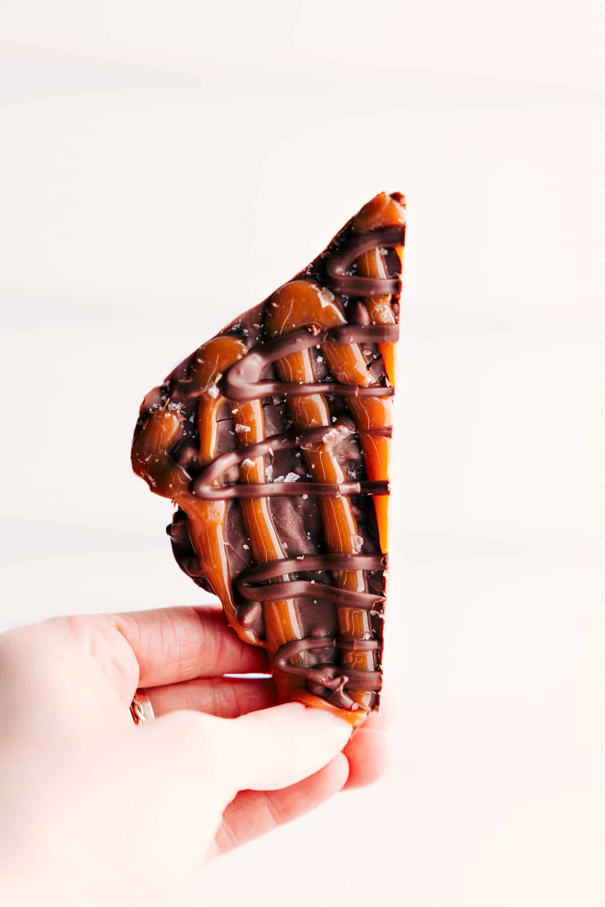 The Best No Bake Treat: Turtle Bark A piece of the turtle bark held up to show the yummy layers of chocolate and caramel.
