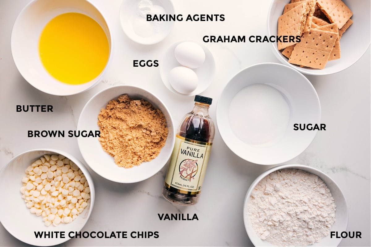 Ingredients In Graham Cracker Cookies All the ingredients in this recipe prepped out for easy assembly including the butter, brown sugar, white chocolate chips, baking agents, eggs, graham crackers, sugar, vanilla, and flour.