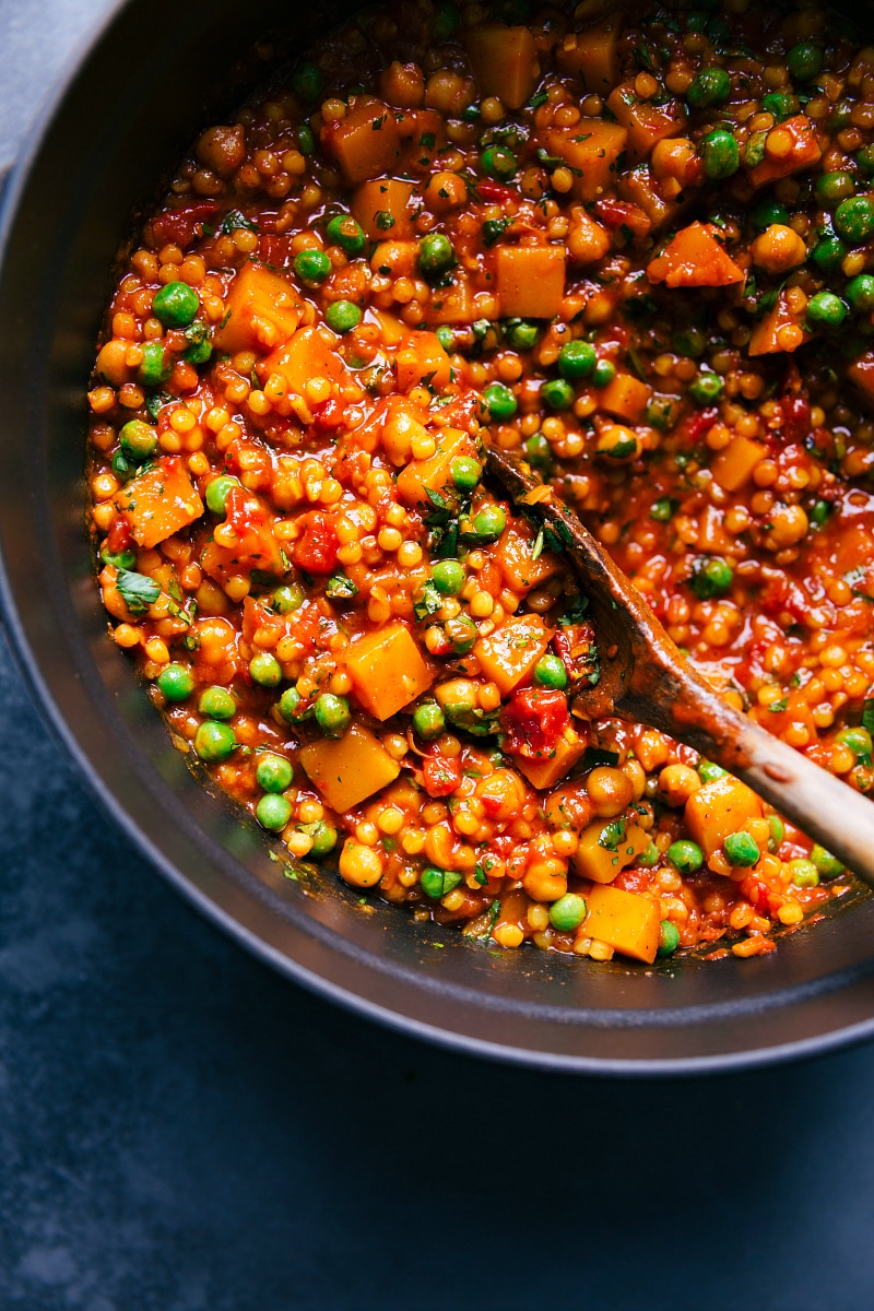 Image of a pan full of Moroccan Stew with a wooden spoon in it.